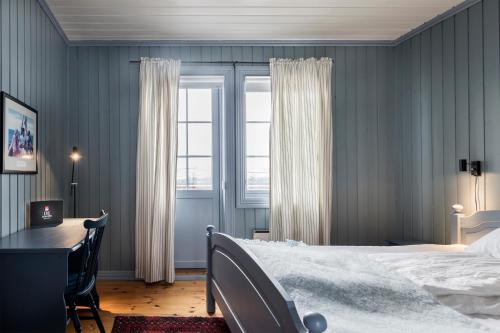 a bedroom with a bed and a desk and a window at Håholmen - by Classic Norway Hotels in Karvåg