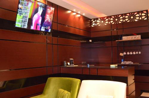 a dining room with a tv and a green chair at شقق برج الشمال للشقق المخدومة Burj Alshmmal serviced apartments in Tabuk