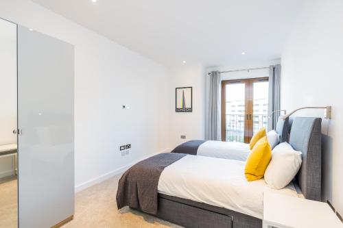 a bedroom with a bed with yellow pillows at St Albans 2 Bed Luxury City Apartment, 5 mins walk to Train & Allocated Parking in St. Albans