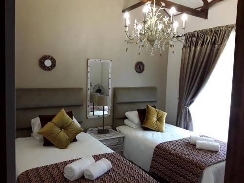 a bedroom with two beds and a mirror and a chandelier at Khumbula Lodge in Underberg