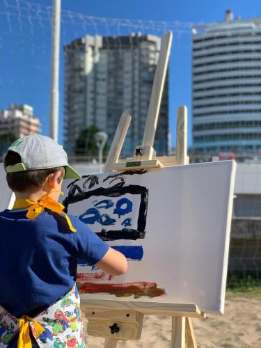 a young boy is painting a cake on an easel at Hotel Costa Galana in Mar del Plata