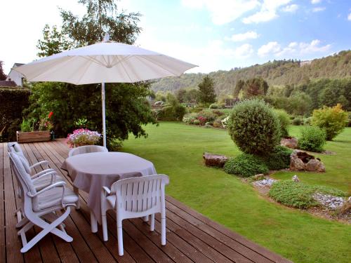 a table and chairs with an umbrella on a deck at B&B Le Clos du Lac in Sart-lez-Spa