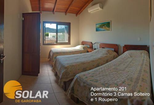 a hotel room with three beds and a window at Solar de Garopaba in Garopaba