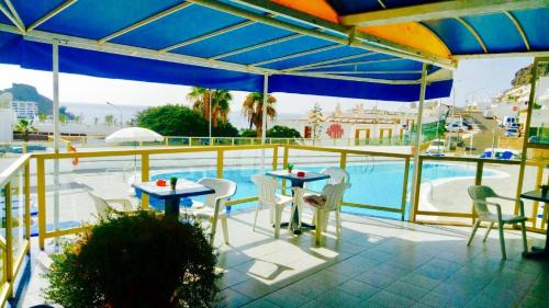 een patio met tafels en stoelen en een zwembad bij Ocean View Design Apartment Puerto Rico in Puerto Rico de Gran Canaria