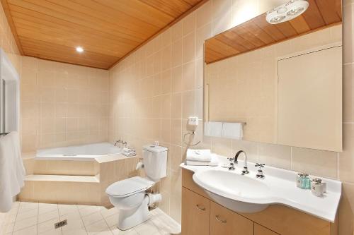 a bathroom with a sink and a toilet and a tub at Checkers Resort in Terrey Hills