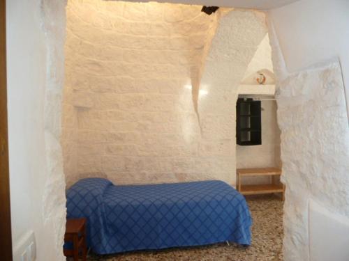 um quarto com uma cama azul numa parede de tijolos em Il Piccolo Trullo em Cisternino