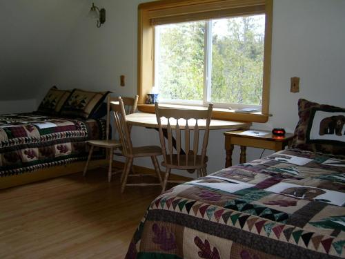 Schlafzimmer mit einem Bett, einem Tisch und einem Fenster in der Unterkunft Sourdough Sunrise B&B in Seward