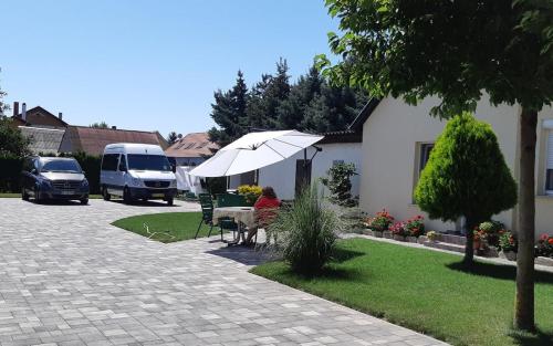 a woman sitting at a table under an umbrella at Elisabeth apartman in Bük