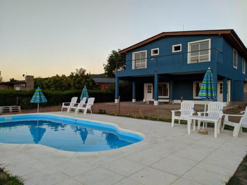 ein blaues Haus mit weißen Stühlen und einem Pool in der Unterkunft Complejo Cielo Azul in Villa Rumipal