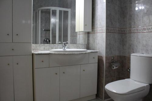 ein Badezimmer mit Waschbecken, Toilette und Spiegel in der Unterkunft CASA CON VISTAS AL MAR EN LA PUNTA DEL CAIMÁN (ISLA CRISTINA) in Isla Cristina