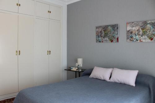 ein Schlafzimmer mit einem Bett und zwei Gemälden an der Wand in der Unterkunft CASA CON VISTAS AL MAR EN LA PUNTA DEL CAIMÁN (ISLA CRISTINA) in Isla Cristina