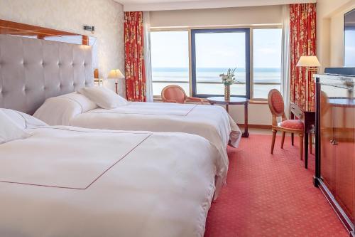 a hotel room with two beds and a large window at Hotel Costa Galana in Mar del Plata