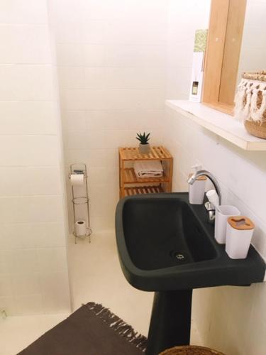 uma casa de banho com um lavatório preto com duas chávenas em Bungalows proche de la plage em Le Gosier