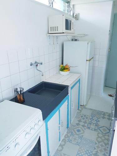uma cozinha com um lavatório e um frigorífico branco em Bungalows proche de la plage em Le Gosier