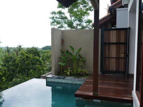 a house with a swimming pool and a wooden deck at Abinawa Hill in Lovina