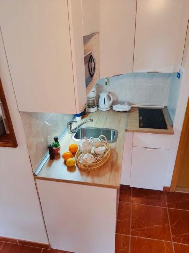 a kitchen with a sink and a basket of fruit on the counter at Apartments Barbaresko in Lumbarda