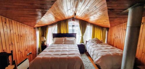 1 dormitorio con 2 camas en una habitación con paredes de madera en Hospedaje Amapola, en Castro