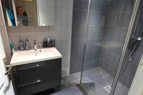 een man die een foto neemt van een badkamer met een douche bij Villa spacieuse lumineuse à Paris in Argenteuil
