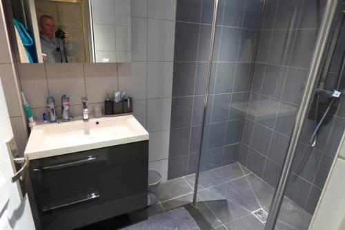 un homme prenant une photo d'une salle de bains avec douche dans l'établissement Villa spacieuse lumineuse à Paris, à Argenteuil