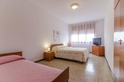 a bedroom with two beds and a tv and a window at Club Villamar - Aygo in Maçanet de la Selva