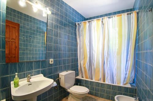 Baño de azulejos azules con aseo y lavamanos en Club Villamar - Rosa del Vents, en Tamariu