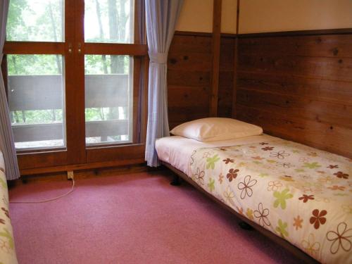 1 dormitorio con 1 cama y 2 ventanas en Hayashi Pension, en Hakuba