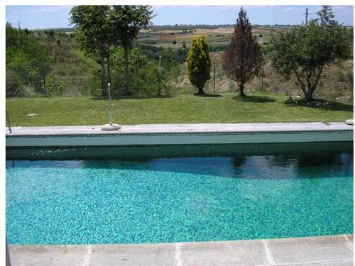 a blue swimming pool with a view of a yard at Morada Campestre a 45 minutos de Madrid in Chozas de Canales