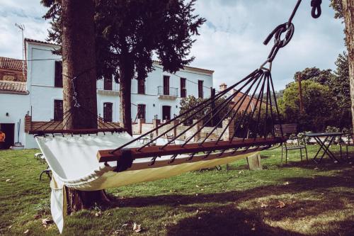 a hammock tied to a tree in front of a building at HOTEL LUZ ALMONASTER in Almonaster la Real