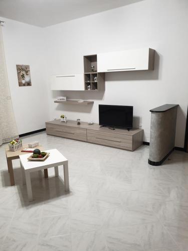 ein Wohnzimmer mit einem TV und einem Tisch in der Unterkunft Casa del Sole - Avola in Avola