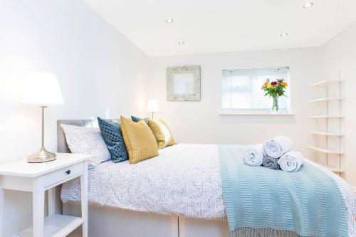Un dormitorio blanco con una cama con toallas. en Stylish 2 Bed Apartment-Zone 2 - 10 Minutes to the heart of London, en Londres