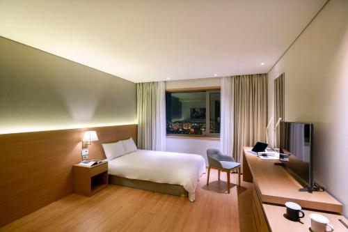 a hotel room with a bed and a desk at Astar Hotel in Jeju