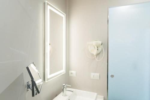 a white bathroom with a sink and a mirror at Novotel Firenze Nord Aeroporto in Sesto Fiorentino