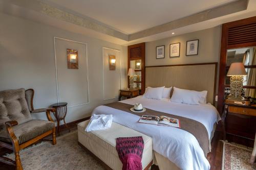 um quarto de hotel com uma cama grande e uma cadeira em Mansion Alcazar em Cuenca