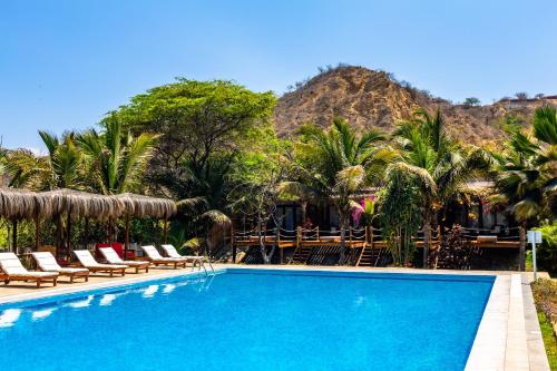 uma piscina com cadeiras e uma montanha ao fundo em Bungalows & Suites Punta Camarón em Zorritos