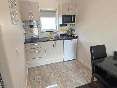 a small kitchen with white cabinets and a sink at BigSky Motels in Omarama