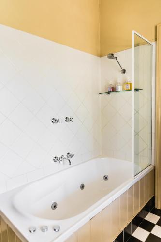 a white bath tub in a bathroom with a shower at Capers Cottage and Barn Accommodation in Wollombi