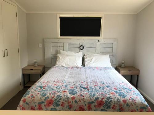 a bedroom with a bed with a floral bedspread at Arches Cottage in Twizel