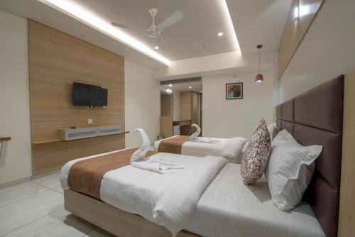 a hotel room with two beds and a flat screen tv at HOTEL SILVERA GRAND in Ahmedabad
