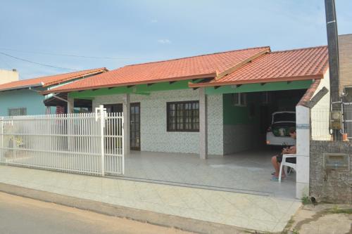 a house with a white fence in front of it at Casa confortável na praia in São Francisco do Sul