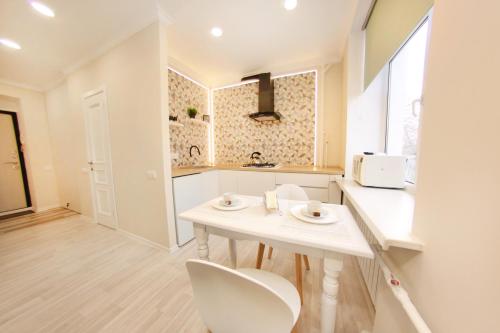 a kitchen with a white table and white chairs at Уютная однокомнатная квартира в историческом центре города in Almaty