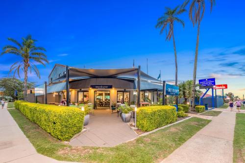 a building with palm trees in front of it at Sugar Country Motor Inn in Bundaberg