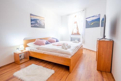 um quarto com uma cama com lençóis brancos e almofadas cor-de-rosa em Apartmán HOREHRONIE em Tale
