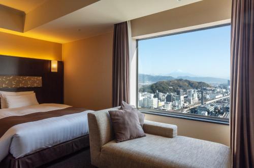 静岡市にあるホテルグランヒルズ静岡(旧ホテルセンチュリー静岡)のベッドと大きな窓が備わるホテルルームです。