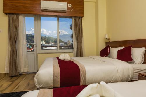 um quarto de hotel com duas camas e uma janela em Hotel Elegant em Pokhara