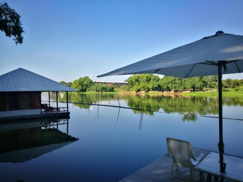 烏泰他尼府的住宿－River Marina Resort，桌子、椅子和水体上的雨伞