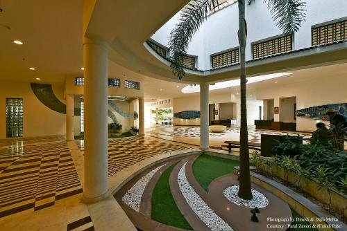 a lobby with a palm tree in a building at Gulmohar Greens Golf & Country Club in Sānand