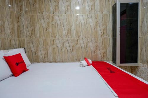 a room with a bed with a red blanket on it at RedDoorz near Kendari Beach 2 in Kendari