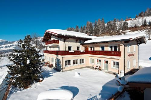 a large house in the snow with a tree at Alpenhof Apartments in Mittersill