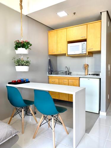 a kitchen with a white table and two blue chairs at STD - Anora Spaces - Stadium Alphaville in Barueri