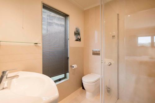 a bathroom with a sink and a toilet and a shower at Hilltop Getaway in Nelson